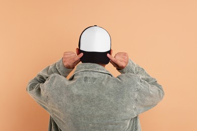 Photo of Man in stylish baseball cap on beige background, back view. Mockup for design