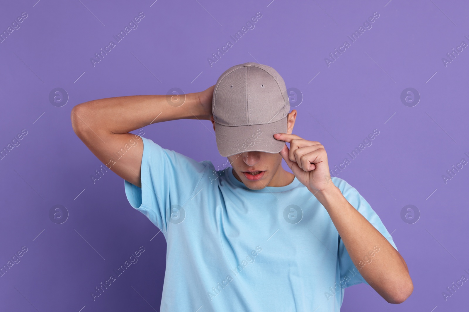 Photo of Man in stylish baseball cap on violet background. Mockup for design