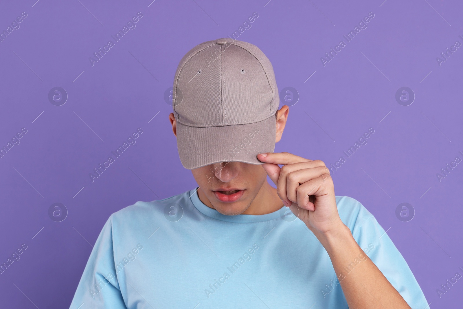 Photo of Man in stylish baseball cap on violet background. Mockup for design