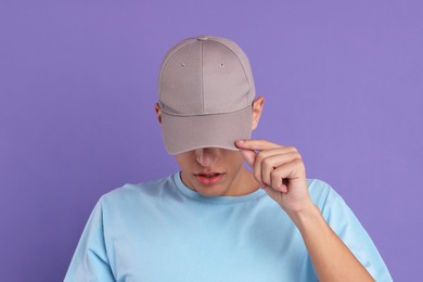 Photo of Man in stylish baseball cap on violet background. Mockup for design