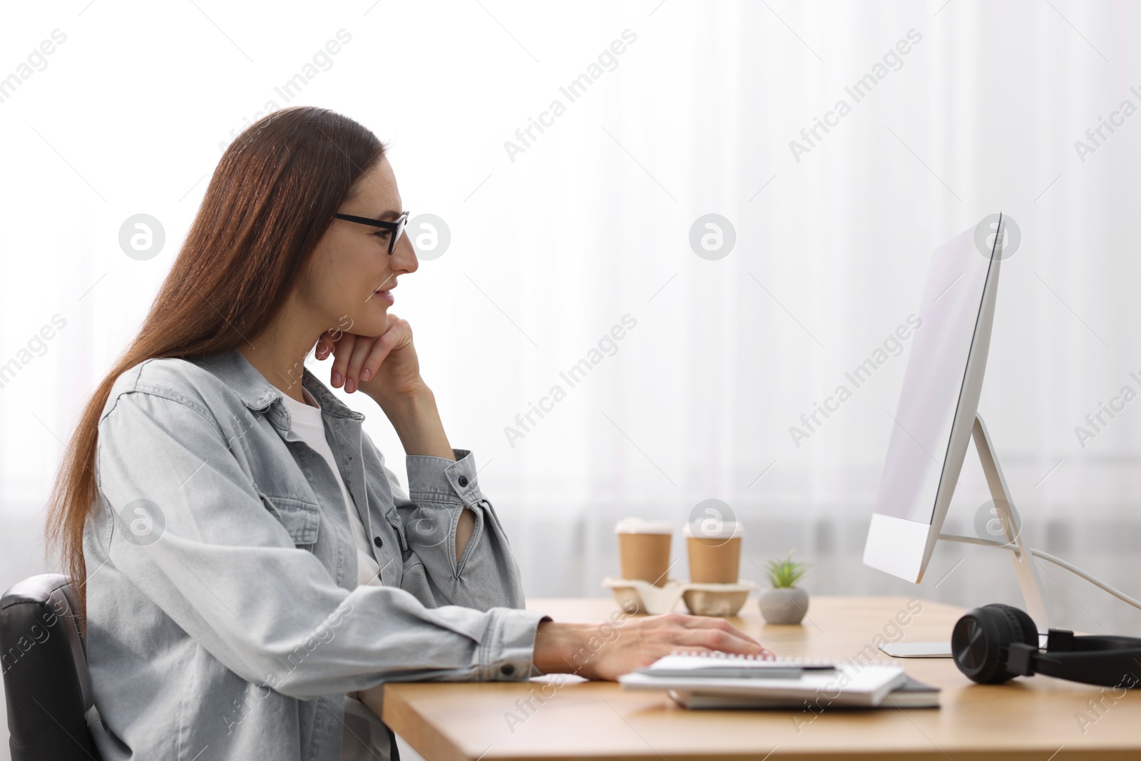 Photo of Programmer working on computer at wooden desk indoors