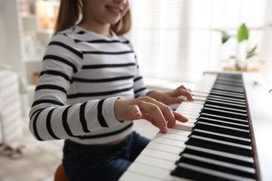 Photo of Girl playing synthesizer at home, closeup. Selective focus