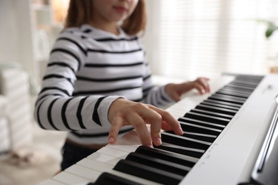 Photo of Girl playing synthesizer at home, closeup. Selective focus