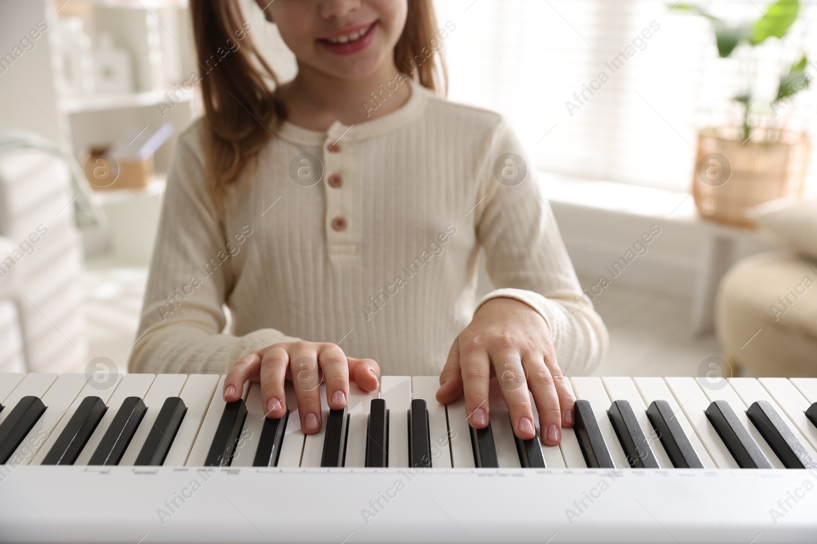 Photo of Girl playing synthesizer indoors, closeup. Electronic musical instrument