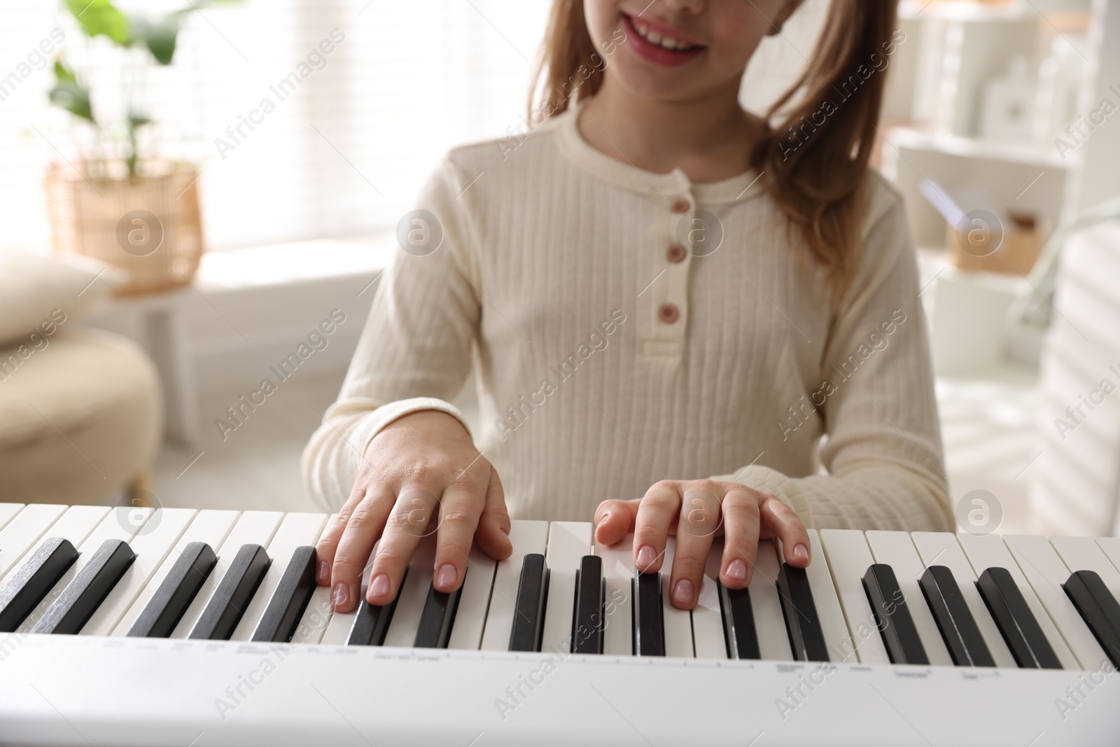 Photo of Girl playing synthesizer indoors, closeup. Electronic musical instrument