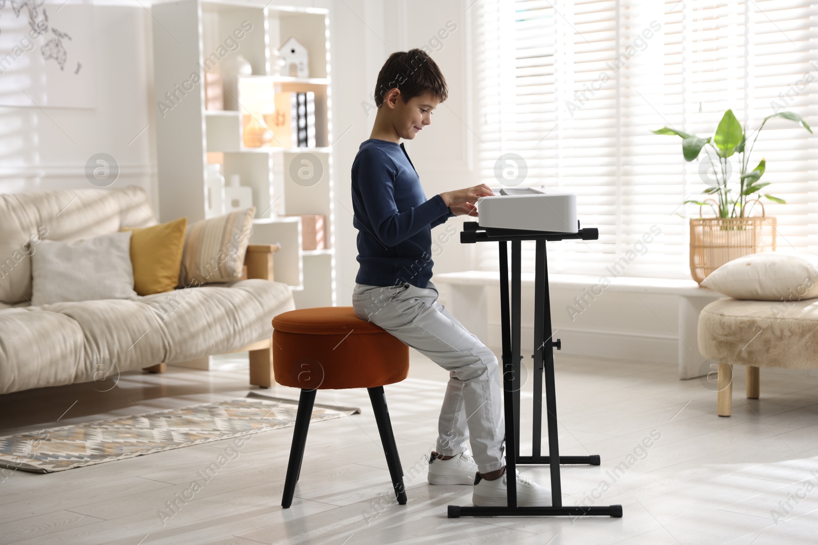 Photo of Little boy playing synthesizer at home. Electronic musical instrument