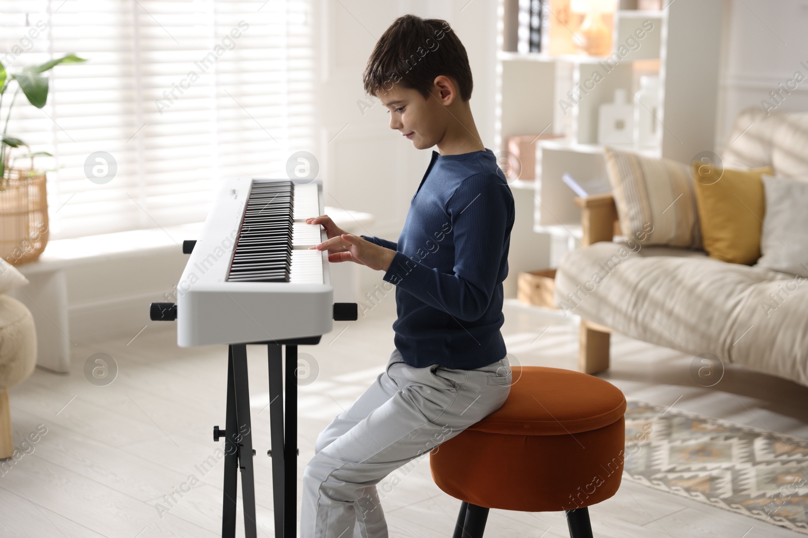 Photo of Little boy playing synthesizer at home. Electronic musical instrument