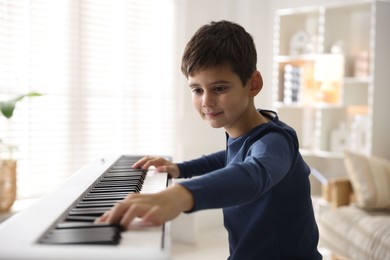 Photo of Cute boy playing synthesizer at home. Electronic musical instrument