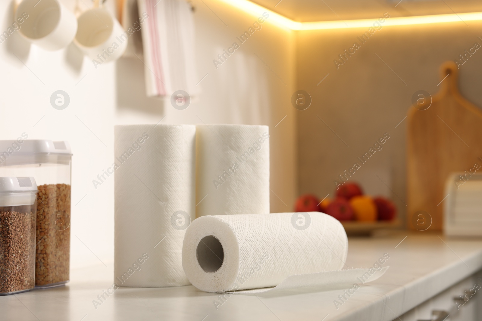 Photo of Rolls of paper towels on white marble countertop in kitchen, space for text