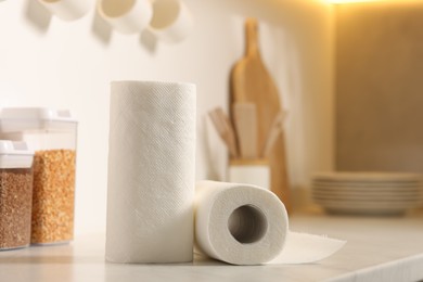 Photo of Rolls of paper towels on white countertop in kitchen, space for text