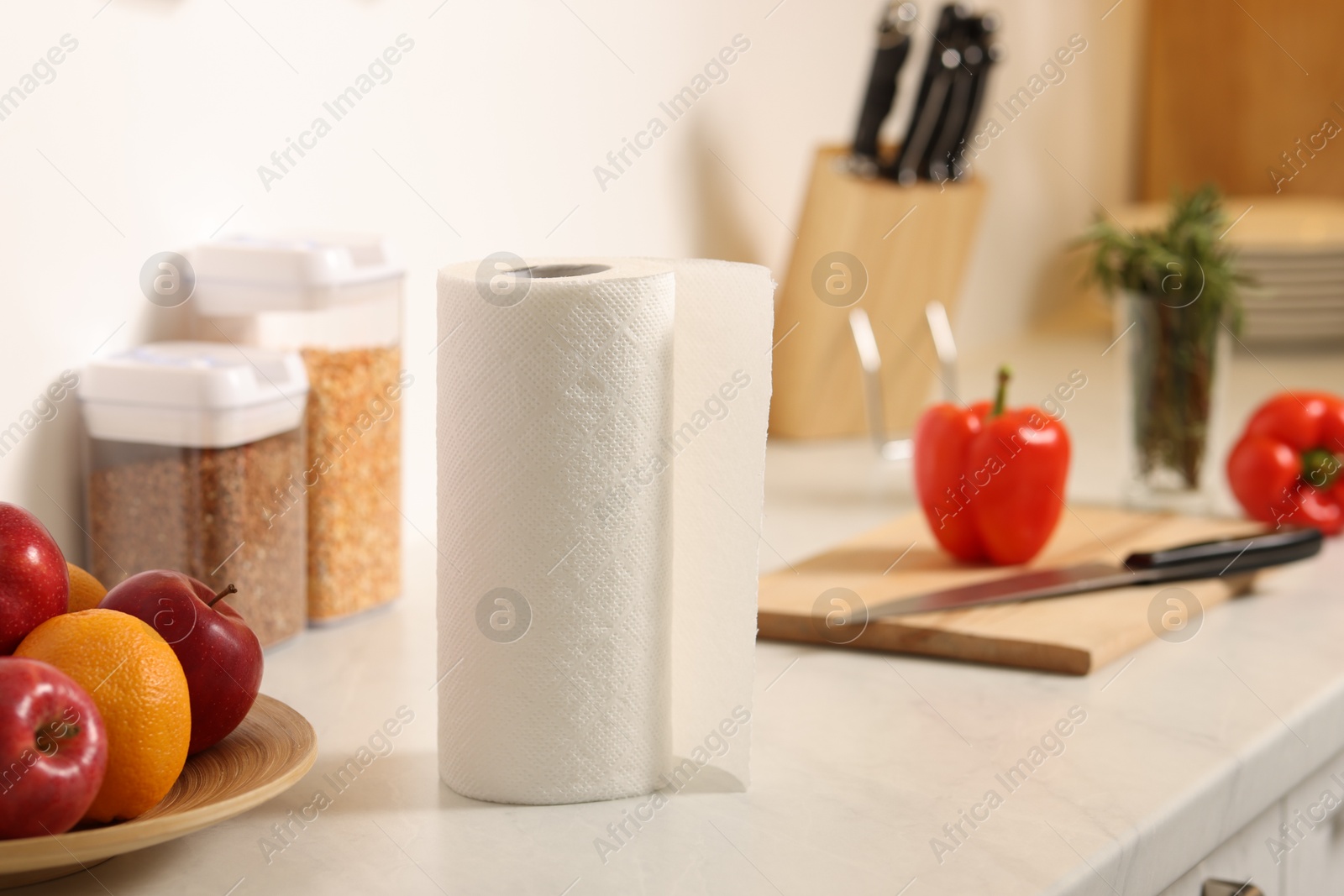 Photo of Roll of paper towels and fruits on white marble countertop in kitchen