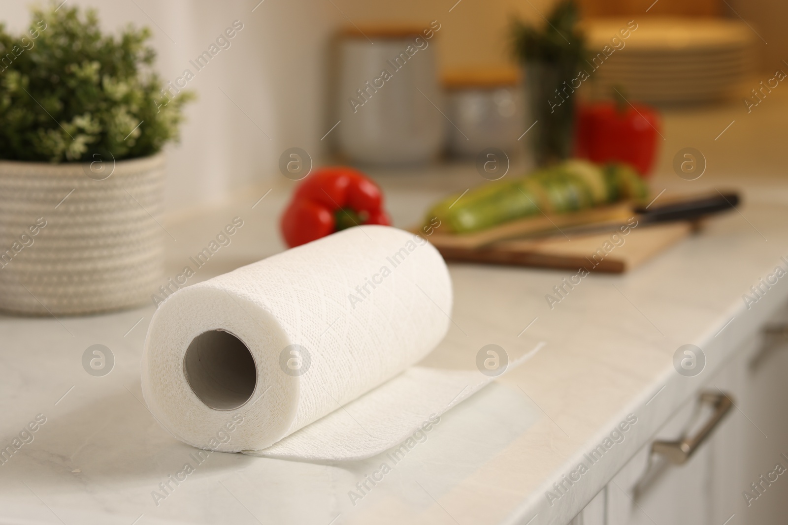 Photo of Roll of paper towels on white marble countertop in kitchen, closeup. Space for text