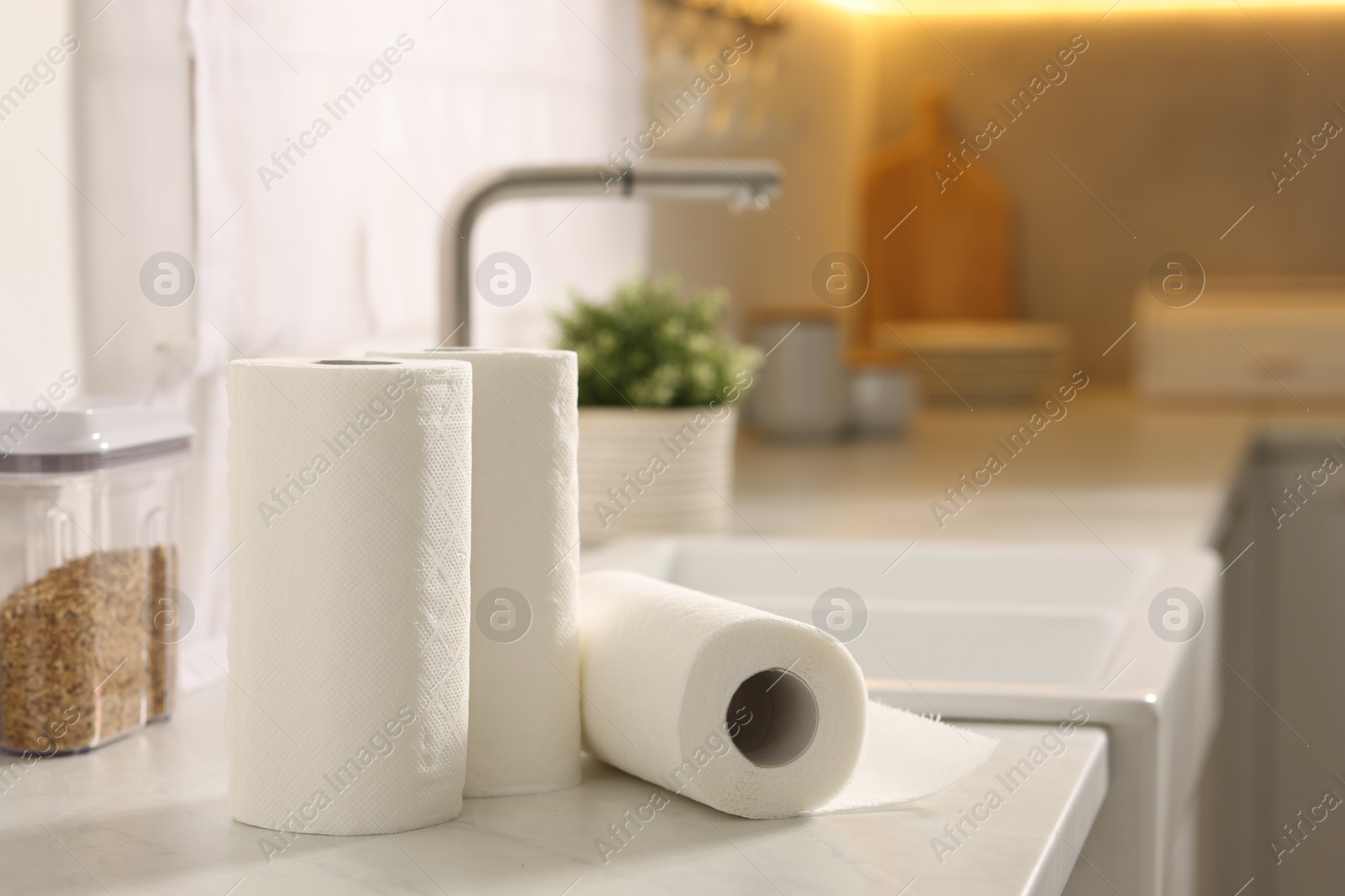 Photo of Rolls of paper towels on white marble countertop in kitchen, space for text