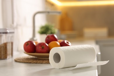 Photo of Roll of paper towels and fruits on white marble countertop in kitchen