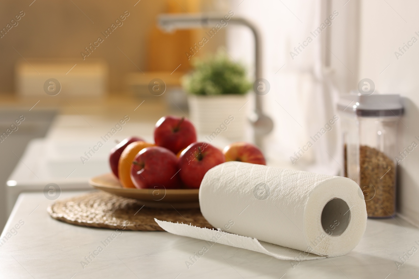 Photo of Roll of paper towels and fruits on white marble countertop in kitchen