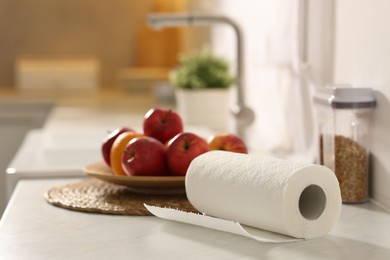 Photo of Roll of paper towels and fruits on white marble countertop in kitchen