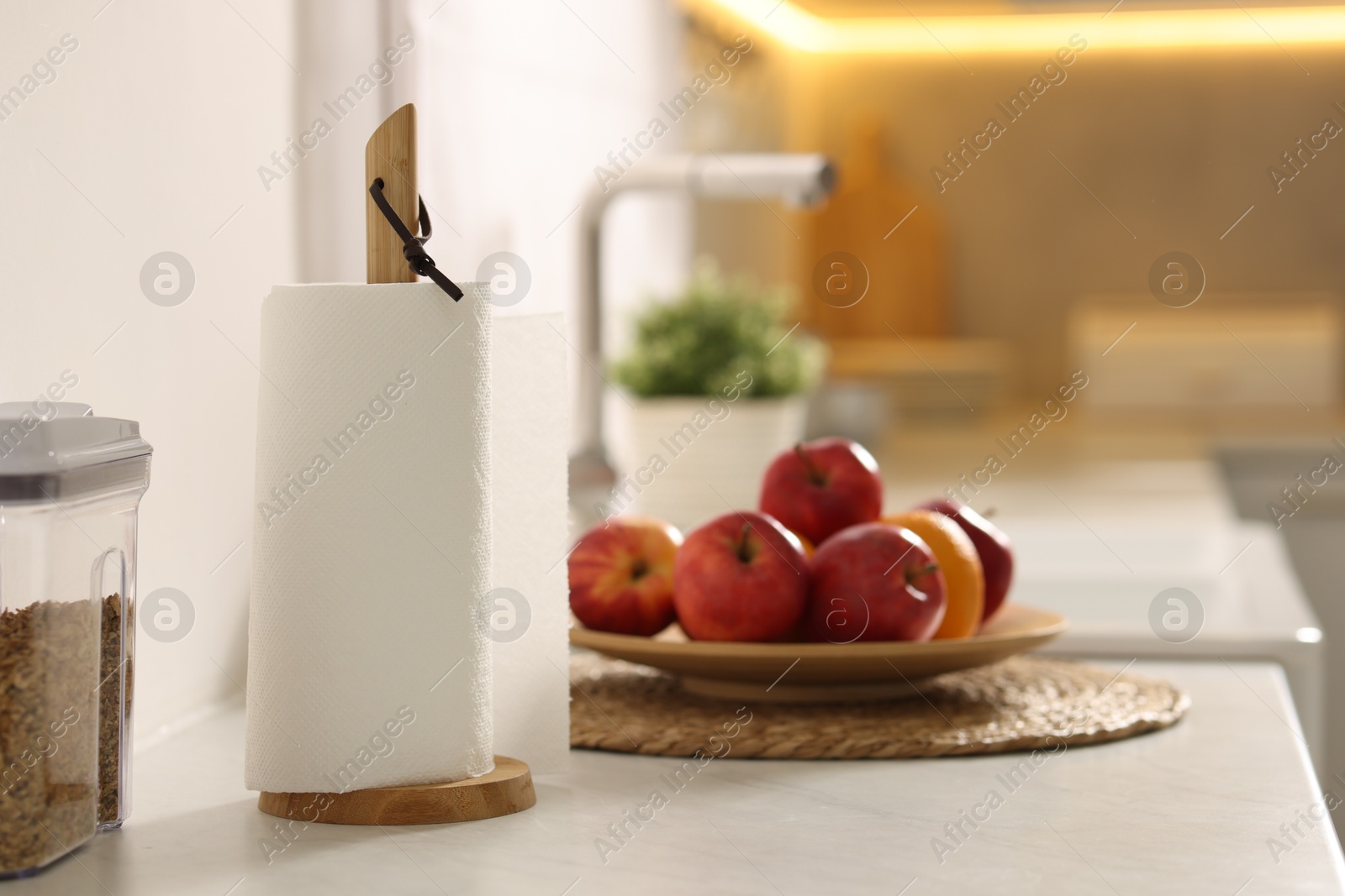 Photo of Roll of paper towels and fruits on white marble countertop in kitchen