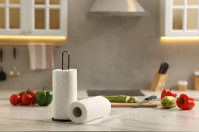 Photo of Rolls of paper towels and vegetables on white marble table in kitchen