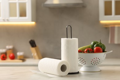 Photo of Rolls of paper towels and vegetables on white marble table in kitchen