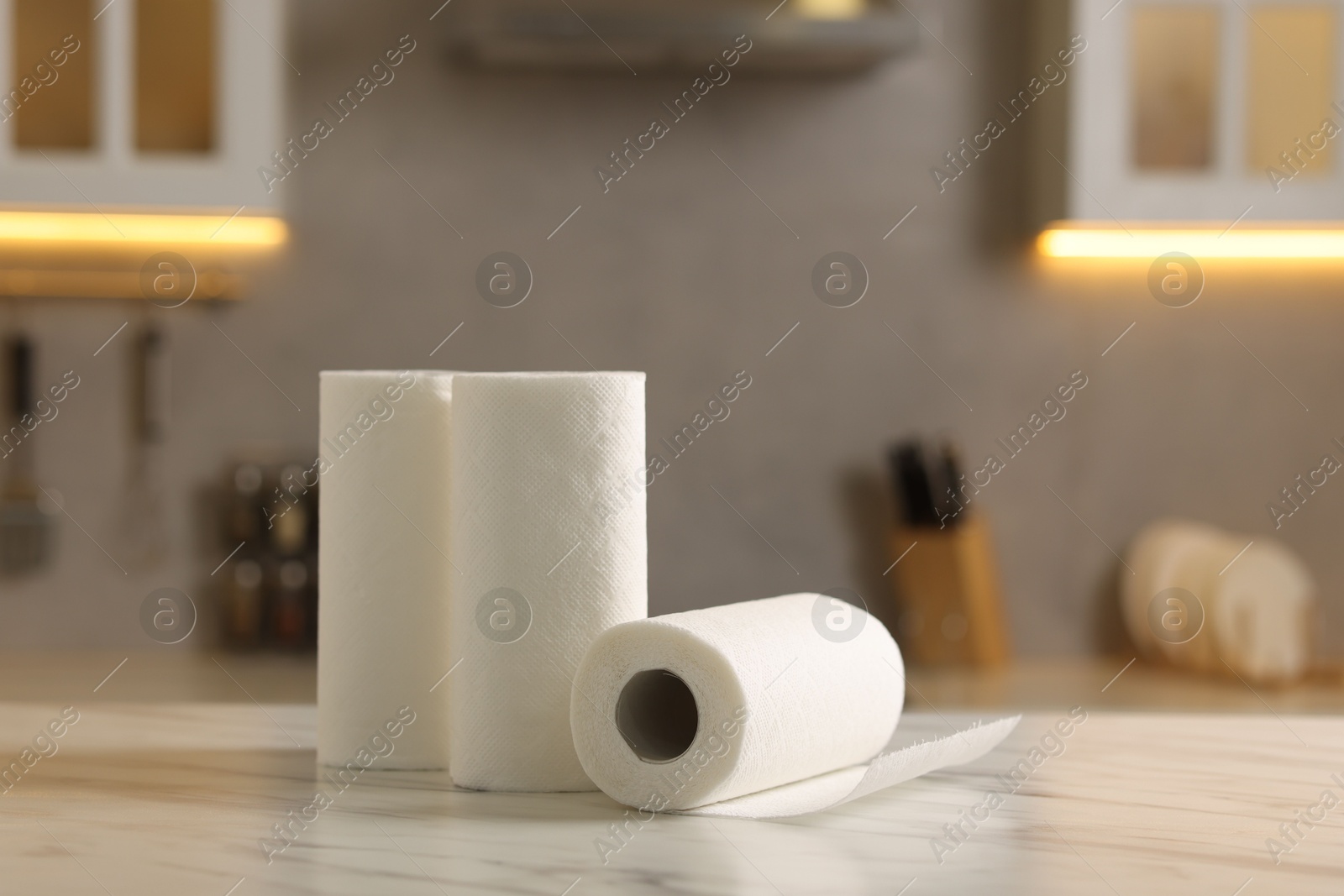 Photo of Rolls of paper towels on white marble table in kitchen, space for text