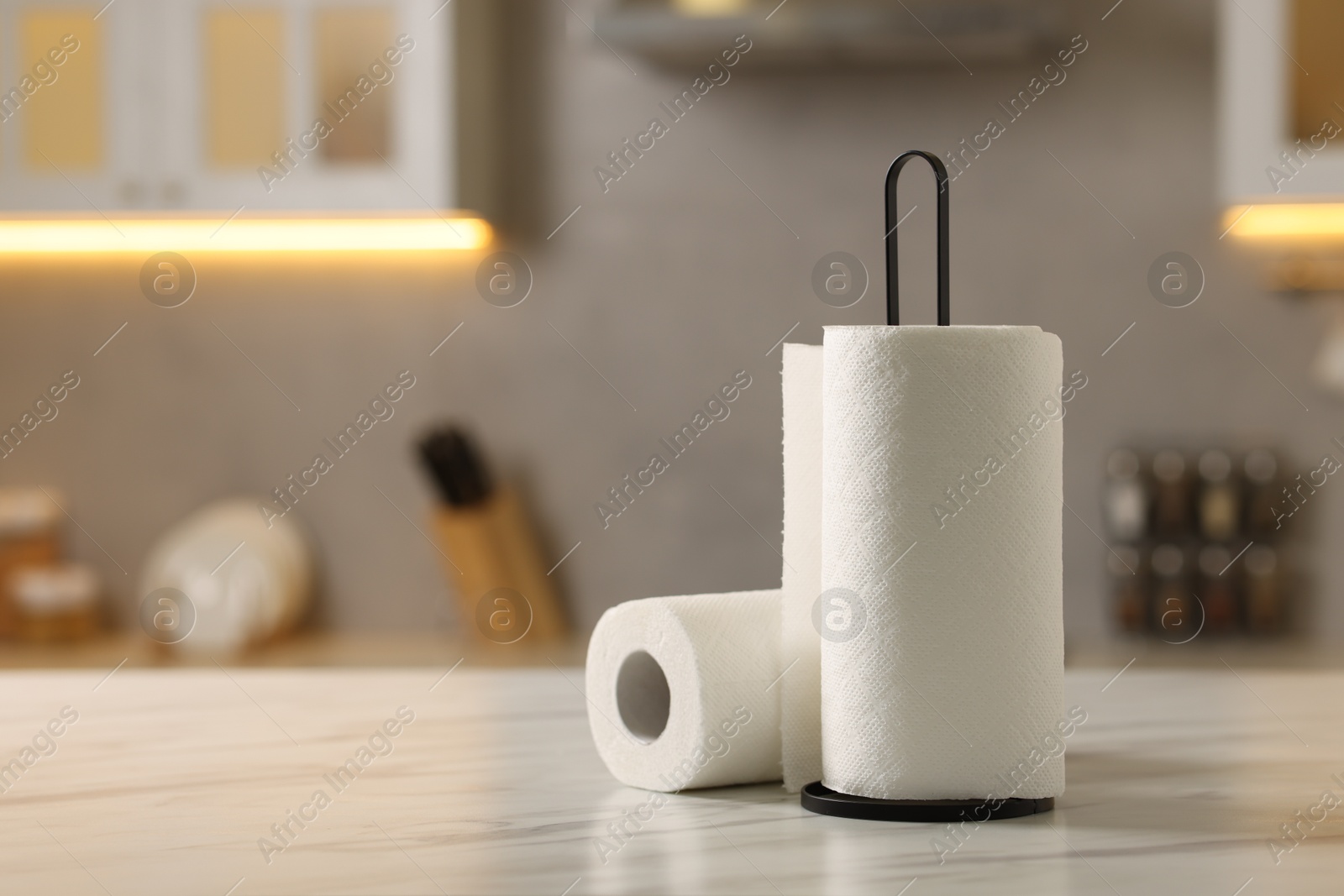 Photo of Rolls of paper towels on white marble table in kitchen, space for text