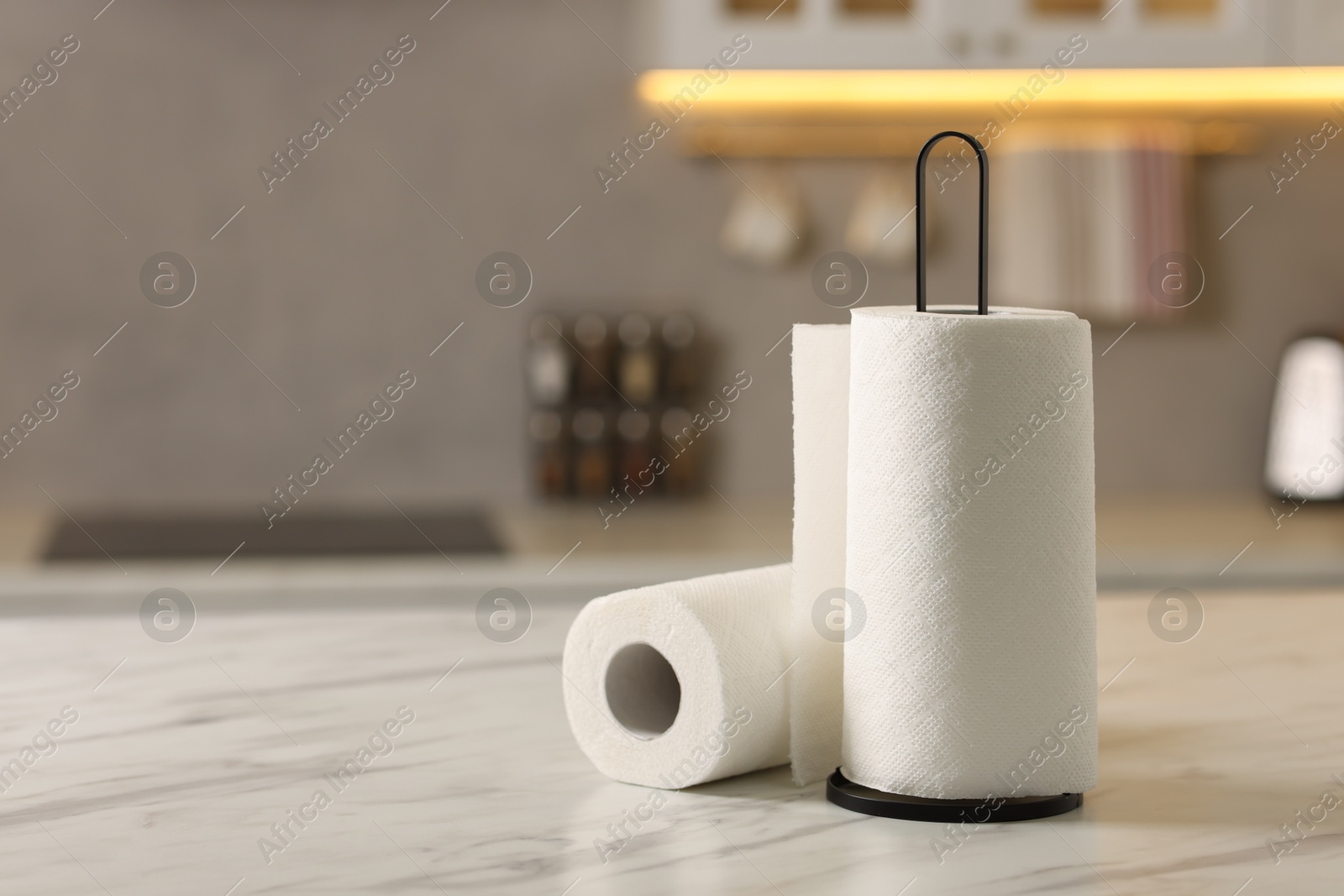 Photo of Rolls of paper towels on white marble table in kitchen, space for text