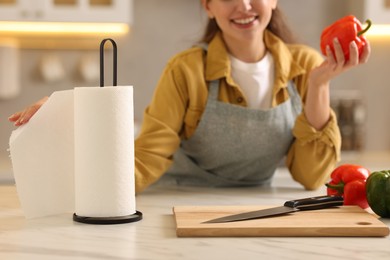 Photo of Woman with bell pepper using paper towels at white marble table in kitchen, closeup