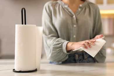 Photo of Woman wiping plate with paper towel at white marble table in kitchen, closeup