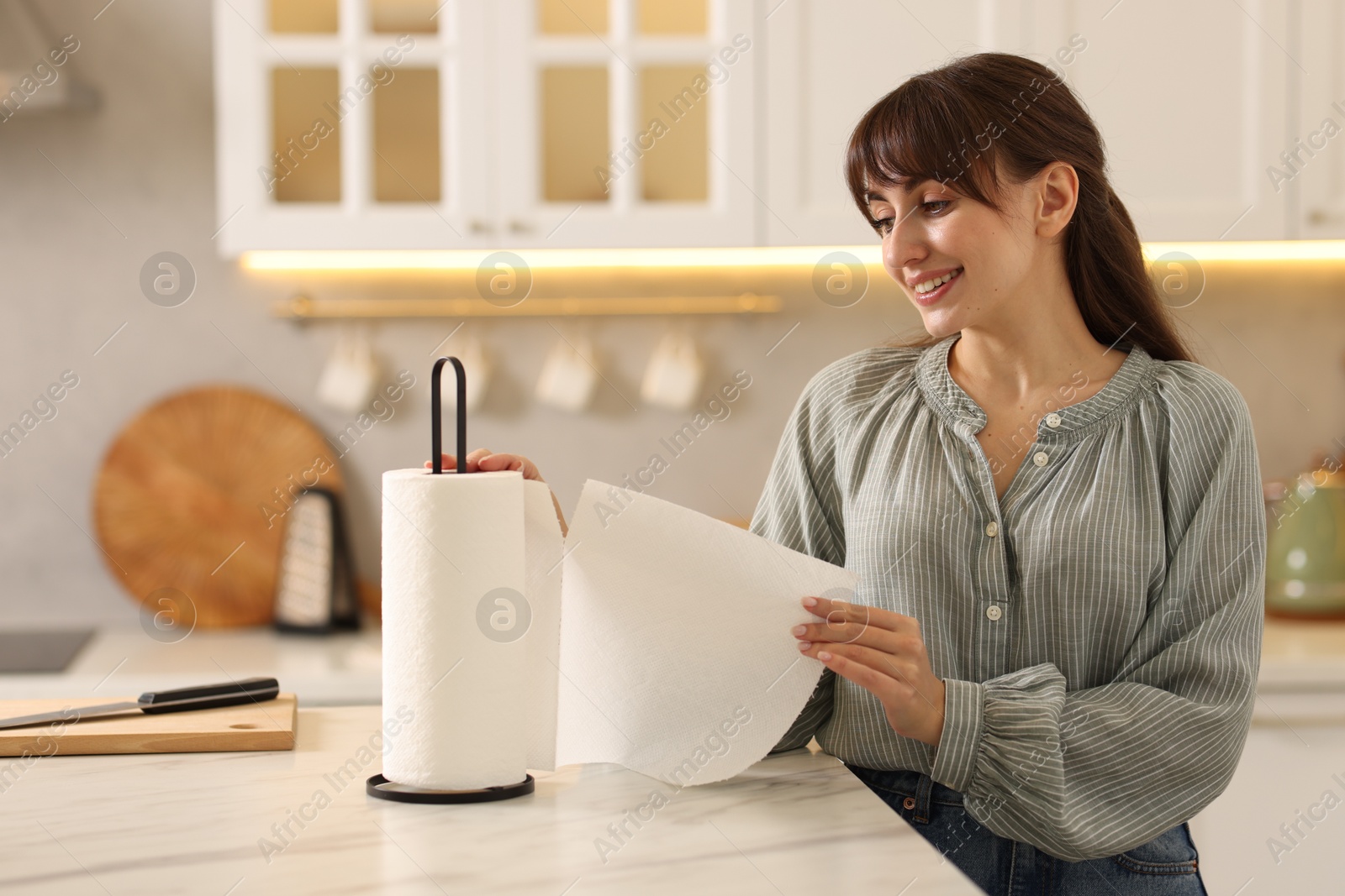 Photo of Woman using paper towels at white marble table in kitchen