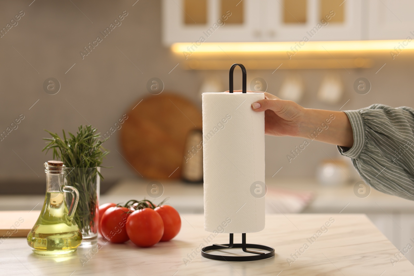 Photo of Woman using paper towels at white marble table in kitchen, closeup