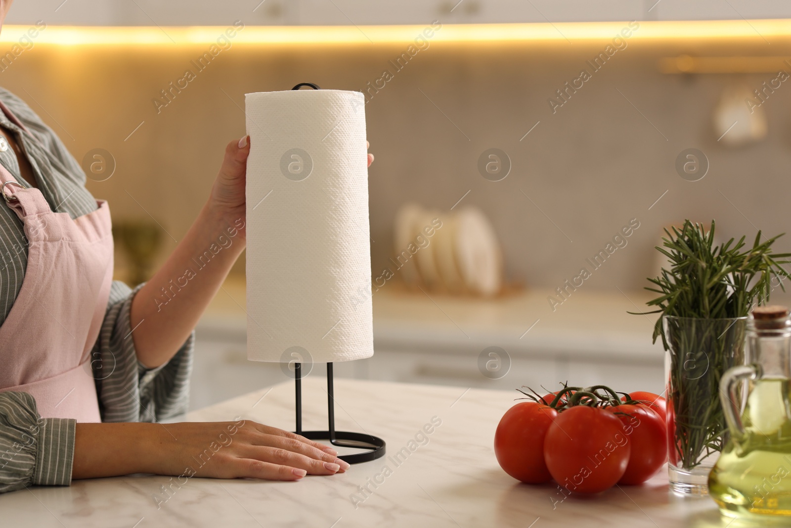 Photo of Woman using paper towels at white marble table in kitchen, closeup