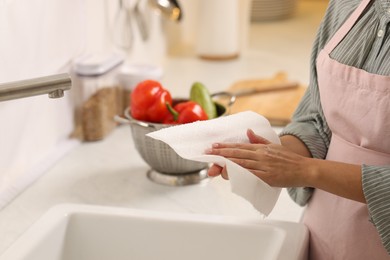 Photo of Woman wiping hands with paper towel in kitchen, closeup