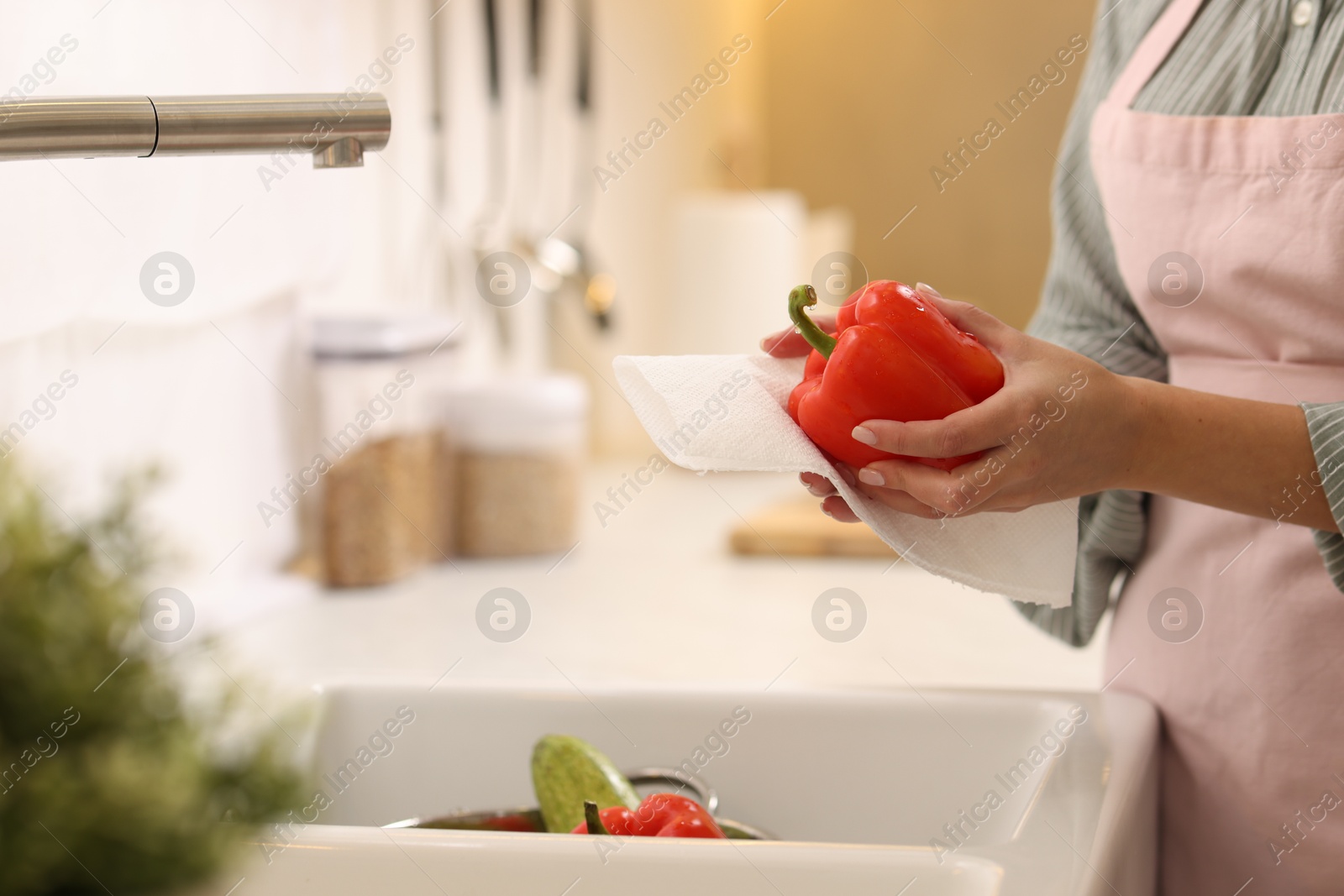 Photo of Woman wiping bell pepper with paper towel in kitchen, closeup