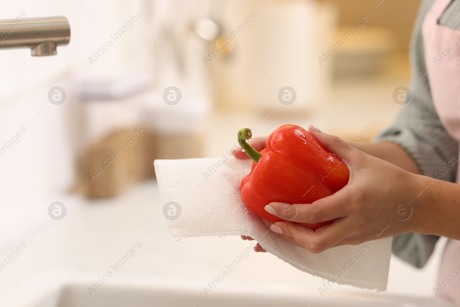 Photo of Woman wiping bell pepper with paper towel in kitchen, closeup