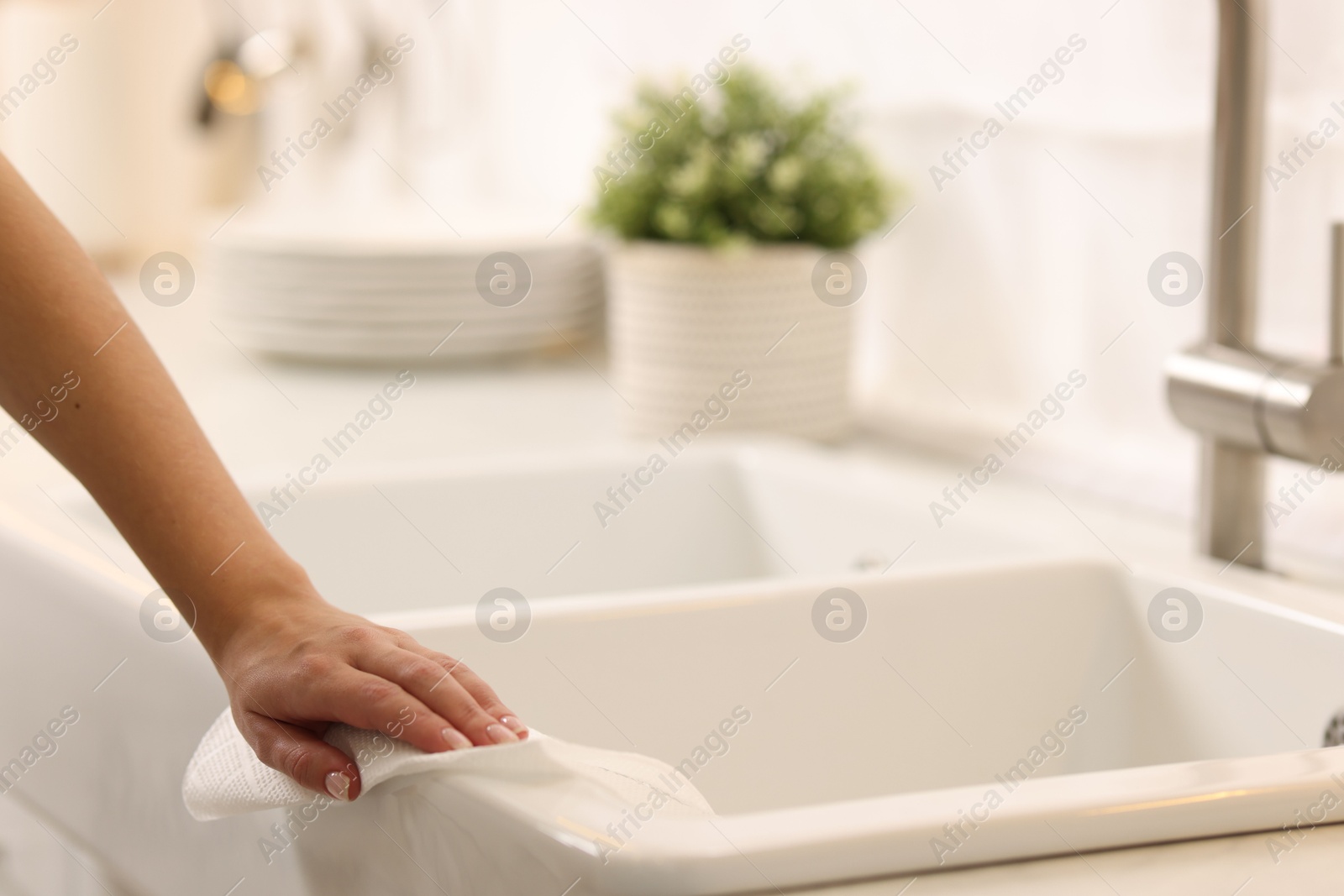 Photo of Woman cleaning sink with paper towel in kitchen, closeup