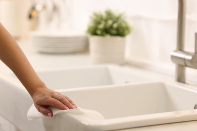 Photo of Woman cleaning sink with paper towel in kitchen, closeup