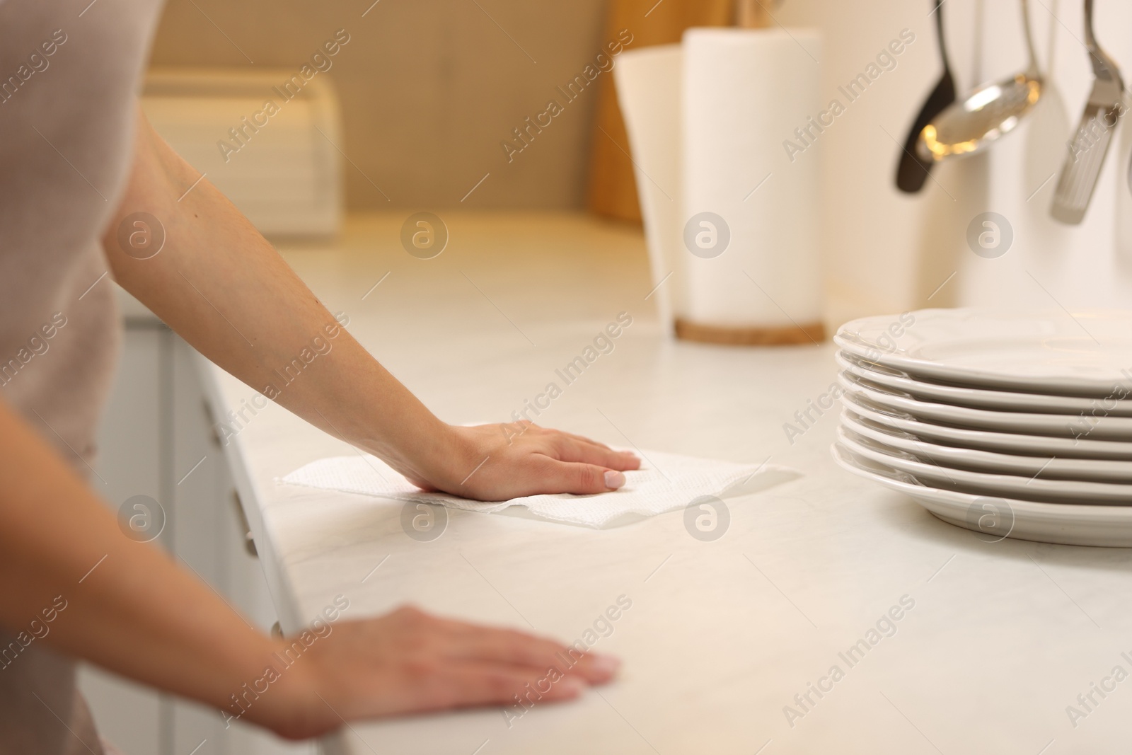 Photo of Woman cleaning countertop with paper towel in kitchen, closeup