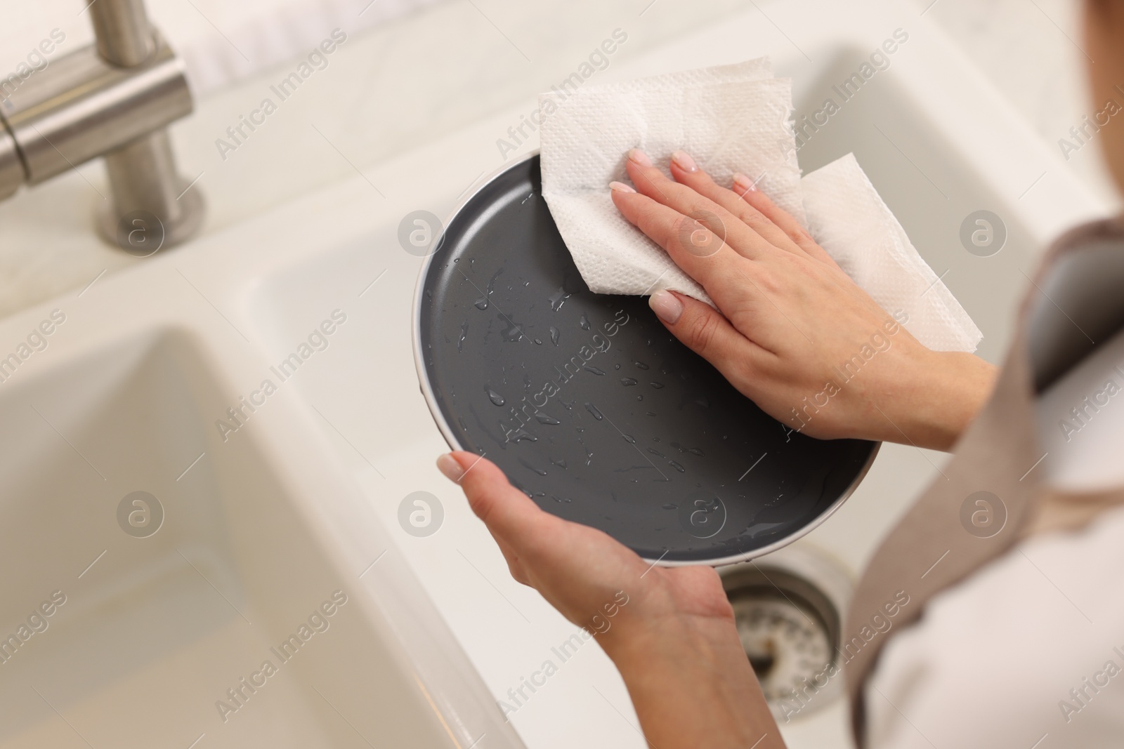 Photo of Woman wiping plate with paper towel in kitchen, above view