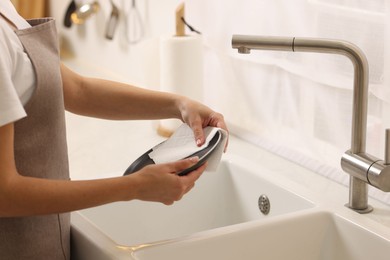 Photo of Woman wiping plate with paper towel above sink in kitchen, closeup