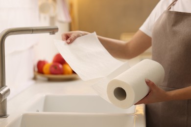 Photo of Woman using paper towels above sink in kitchen, closeup