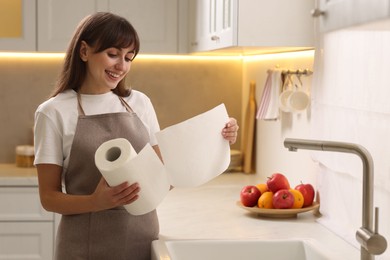 Photo of Happy woman using paper towels in kitchen