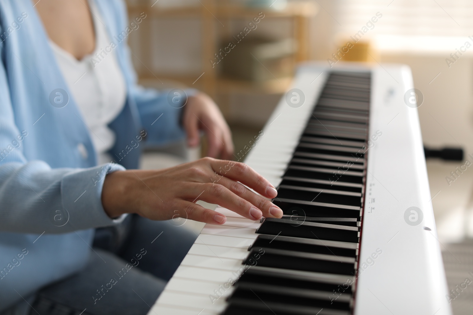 Photo of Woman playing synthesizer indoors, closeup. Electronic musical instrument