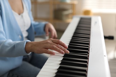 Photo of Woman playing synthesizer indoors, closeup. Electronic musical instrument