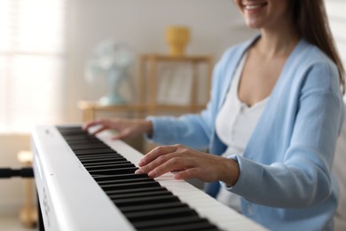 Photo of Woman playing synthesizer indoors, closeup. Electronic musical instrument