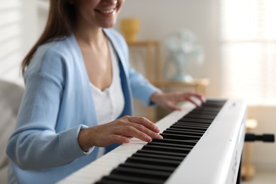 Photo of Woman playing synthesizer indoors, closeup. Electronic musical instrument