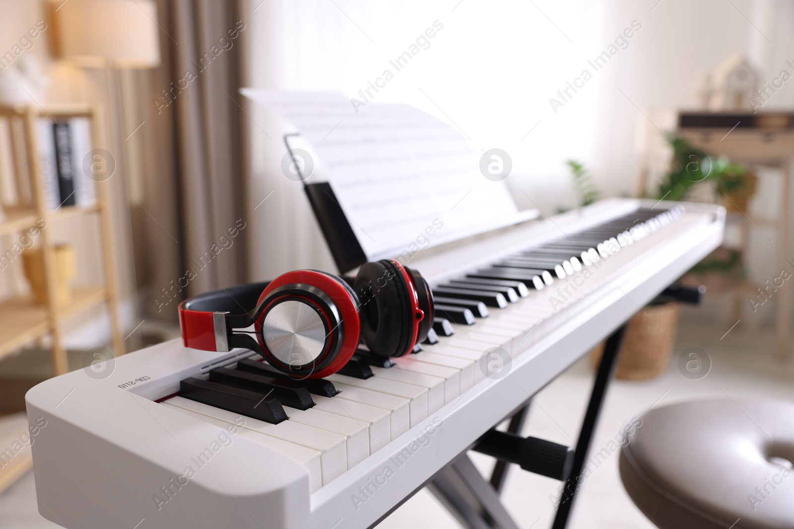 Photo of Synthesizer with music sheets and headphones indoors, closeup