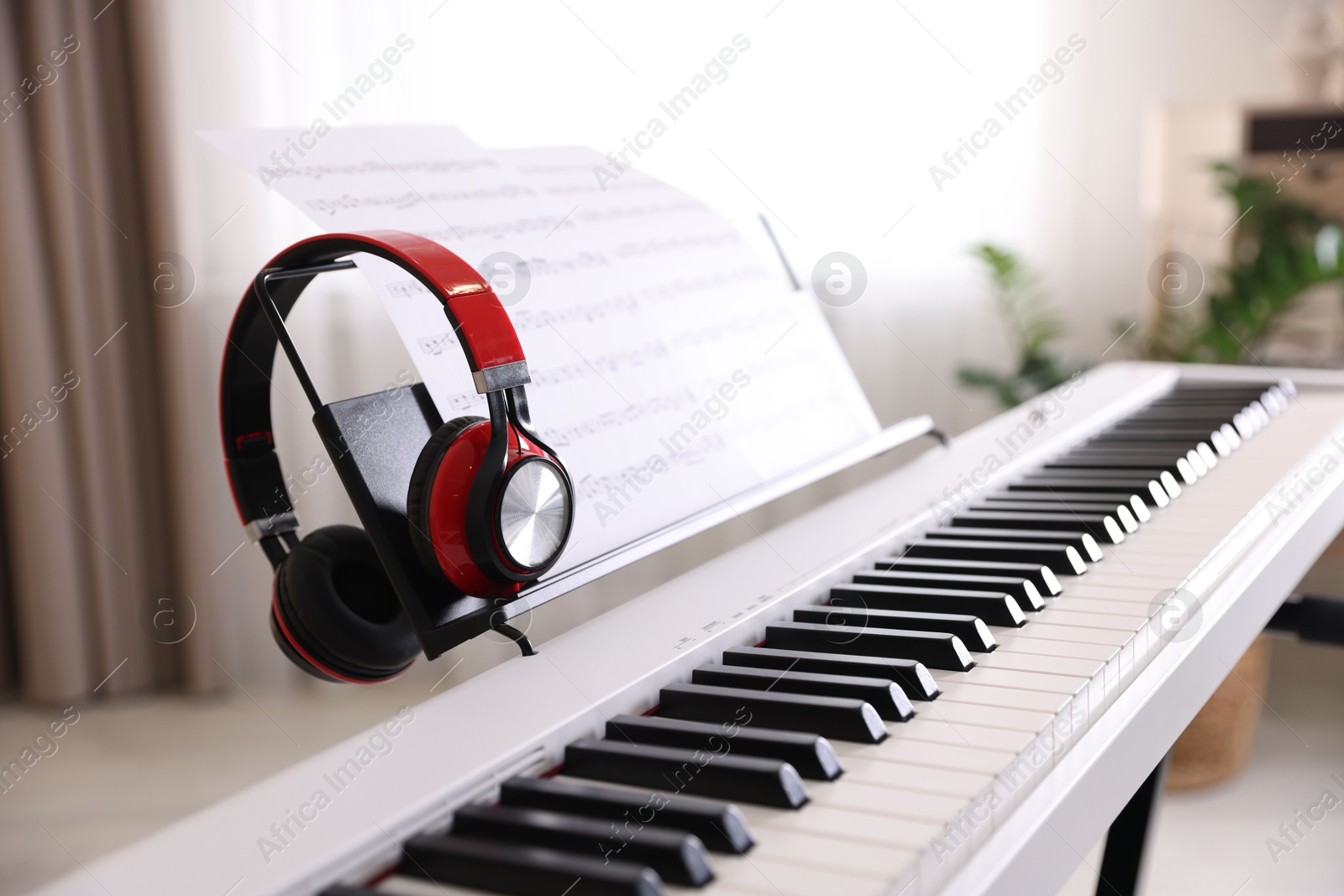 Photo of Synthesizer with music sheets and headphones indoors, closeup