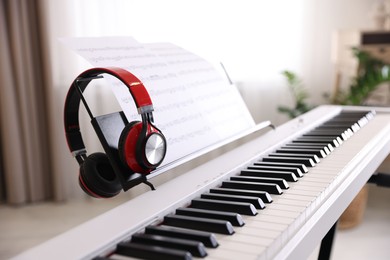 Photo of Synthesizer with music sheets and headphones indoors, closeup