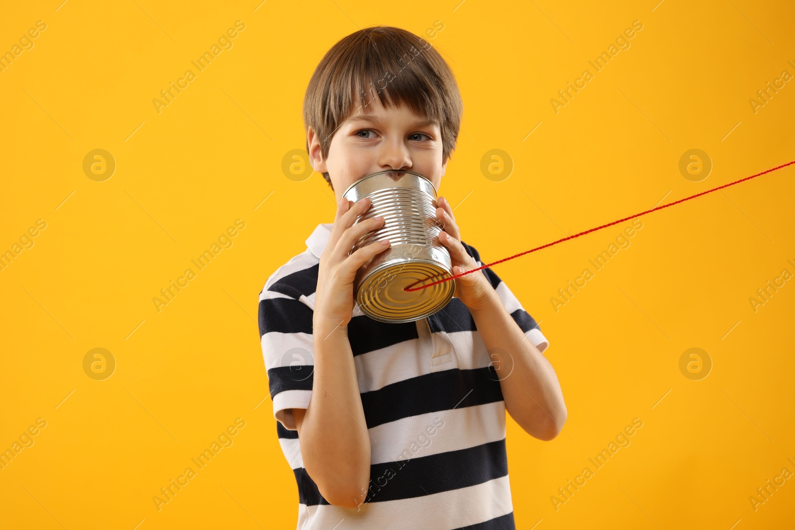 Photo of Boy using tin can telephone on yellow background