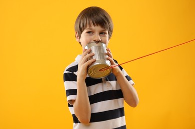 Photo of Boy using tin can telephone on yellow background